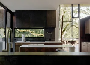 Modern residential kitchen featuring metal, glass, and concrete materials.