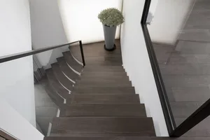 Modern staircase with wooden steps and glass railings.