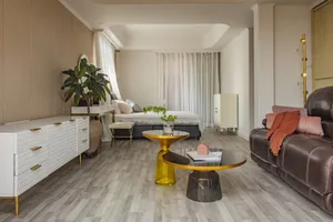 A minimalist living room featuring a wooden floor, a brown leather sofa, and a white cabinet. The room has a modern, clean de