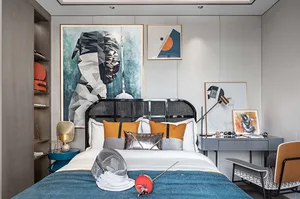 A modern bedroom featuring a black metal bed frame, geometric abstract art, and a blue blanket with colorful pillows.