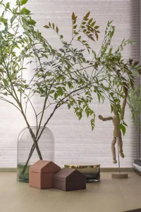 A modern decorative planter with green leaves and house-shaped boxes on a wooden surface.