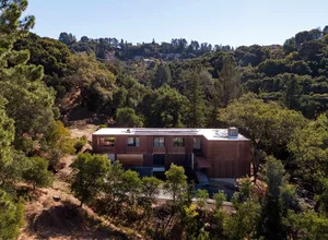 A modern residential house with wood exterior surrounded by trees.