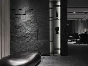 A minimalist black and white scene featuring textured black metal furniture against a textured black wall.