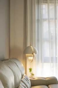 A modern living room with white curtains and a leather couch.