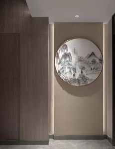 Circular artwork featuring a mountainous landscape design mounted on a wall with a textured finish.