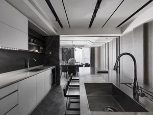 A sleek, modern kitchen with metallic black finishes, white countertops, and a large island.