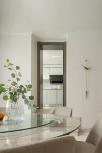 Modern minimalist kitchen with glass table, marble countertops, and wooden accents.