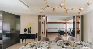 A modern dining room with a marble table and chairs, featuring contemporary lighting and minimalist decor.
