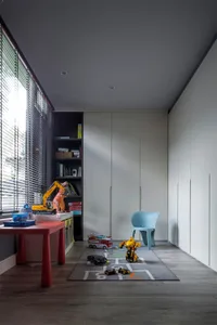 A minimalist playroom with wall storage, featuring a red table, wooden floor, and toys on a hopscotch mat.