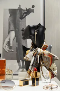 A black mannequin head adorned with a patterned scarf and gold dangling earrings, surrounded by various accessories such as p