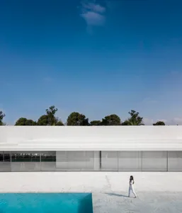 A minimalist architectural exterior with large glass panels and a clear blue sky.