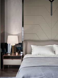 A minimalist bedroom with neutral-toned materials, showcasing a bed with white pillows and a gray blanket, accompanied by a m
