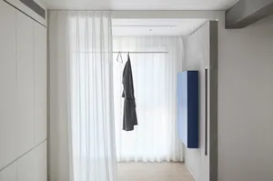 A minimalist closet area featuring white curtains and clothing storage.