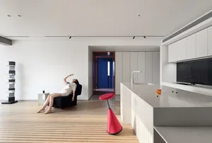 A minimalist living room featuring concrete walls and wooden flooring.
