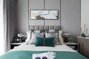 A modern bedroom featuring a bed with a white comforter, green throw blanket, and various pillows arranged neatly.