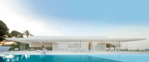 Modern house exterior with large glass windows and white concrete.