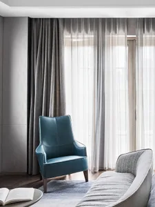 A modern living room featuring a blue leather armchair and grey curtains.