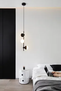 A minimalist bedroom with white walls, a black wardrobe, a white bed, a white bedside table, and a modern light fixture.