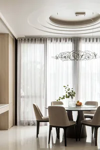 Modern minimalist dining room with glass table, upholstered chairs, and transparent curtains