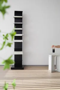 A minimalist black metal shelving unit against a white wall with books.