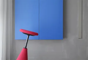 Modern interior design with a blue backdrop, featuring a dominant red stool.
