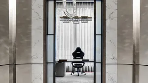 Executive office with marble walls and floor, featuring a black office chair and table, and a crystal chandelier.