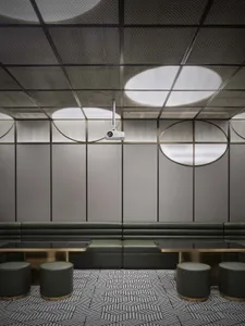 Modern industrial restaurant dining room with metallic textured panels and green leather seating.