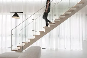 A modern staircase with glass railings and wooden steps in a minimalist interior design setting.