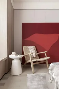 A minimalist bedroom with a wooden frame chair and a red abstract painting on the wall.