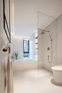 Modern bathroom featuring marble accents and a glass enclosure in a minimalist design.