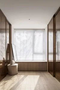 Modern, minimalist living room with a window seat and wood flooring.