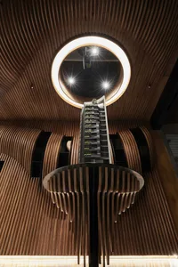A modern lobby with wooden interiors and a circular ceiling light.