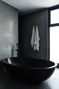 Modern minimalist bathroom featuring a sleek black bathtub made of marble.