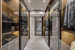 Modern closet and bathroom with wooden, glass, and marble features.