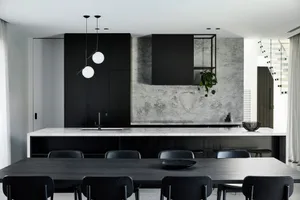 Modern kitchen interior with marble countertops and black fixtures.