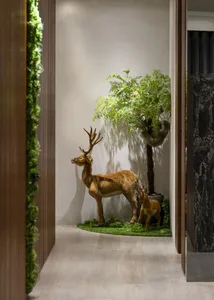 A decorative deer figurine with a small calf, surrounded by artificial greenery in a corner space.