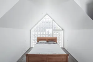 Modern minimalist bedroom with a wooden bed and geometric window