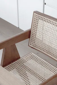 Detail of a minimalist wooden chair with woven rattan backrest and seat.