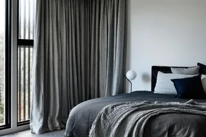 A modern bedroom featuring soft textiles, designed for relaxation and comfort.