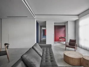 A modern living room with a grey leather sofa and wooden coffee table, under a ceiling with recessed lighting.