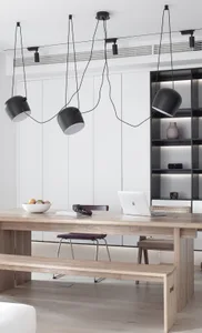 Modern dining room featuring a wooden table with a laptop and a bowl of fruit.