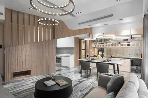 A modern living, dining, and kitchen space featuring wooden paneling and a marble countertop.