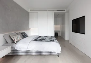 Modern minimalist bedroom with a built-in bed, sleek white cabinets, and wooden flooring.
