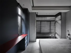 Minimalist bedroom with black blinds, white sheets, and concrete walls