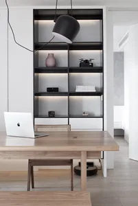 A modern minimalist home office featuring a wooden desk, metal lamp, and glass shelves.