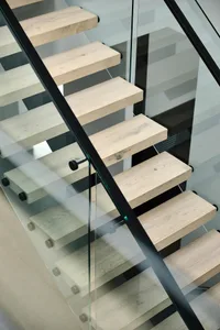 Modern wooden stairs with a glass railing.
