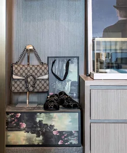 A luxury retail display featuring a Gucci purse, loafers, and a framed picture on a wooden dresser.