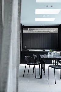 A modern industrial-style kitchen with metal chairs and black elements.