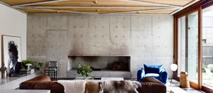 Industrial-style interior space with concrete walls, brown leather sofas, and blue armchair.