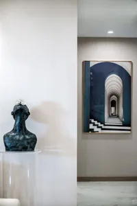 A modern sculpture of a human bust with a lightbulb on its head, placed on a light pedestal.